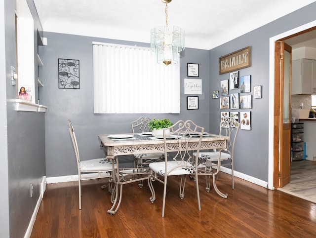 dining area with a notable chandelier and dark hardwood / wood-style flooring