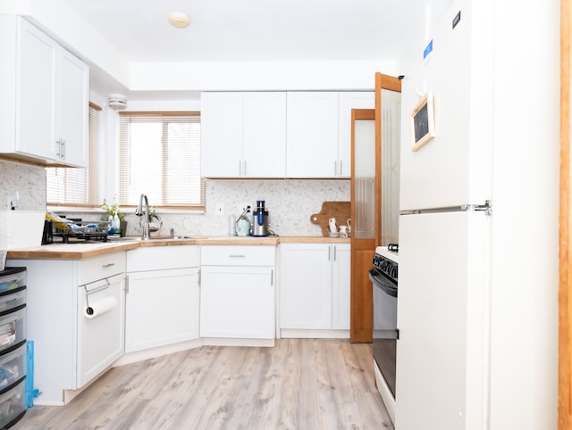 kitchen featuring white cabinets, white refrigerator, black range with electric stovetop, and light hardwood / wood-style floors