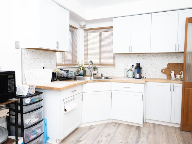 kitchen featuring light wood-type flooring, white cabinetry, sink, and tasteful backsplash