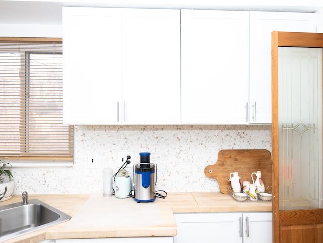 kitchen featuring white cabinets, tasteful backsplash, and sink