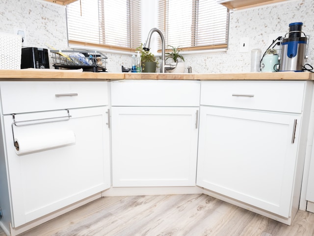 kitchen with white cabinetry, sink, and light wood-type flooring