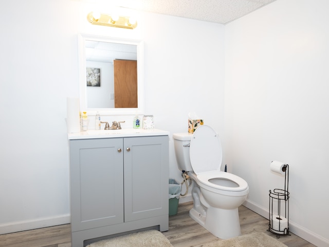 bathroom featuring vanity, wood-type flooring, a textured ceiling, and toilet