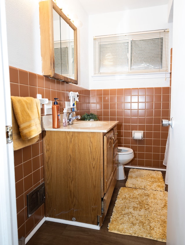 bathroom with vanity, toilet, and tile walls