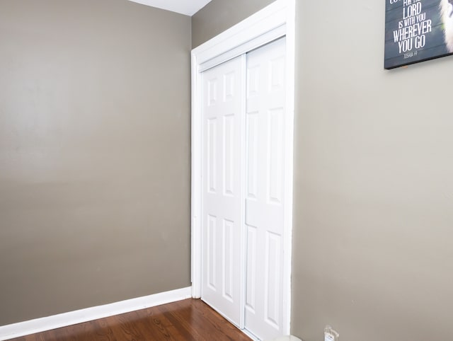 unfurnished bedroom with dark wood-type flooring and a closet