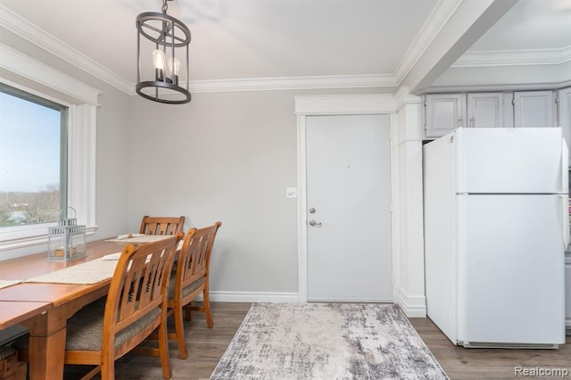 dining room featuring crown molding, baseboards, wood finished floors, and a notable chandelier