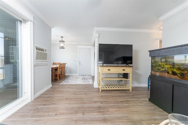 living room featuring an AC wall unit, baseboards, ornamental molding, and light wood-style floors