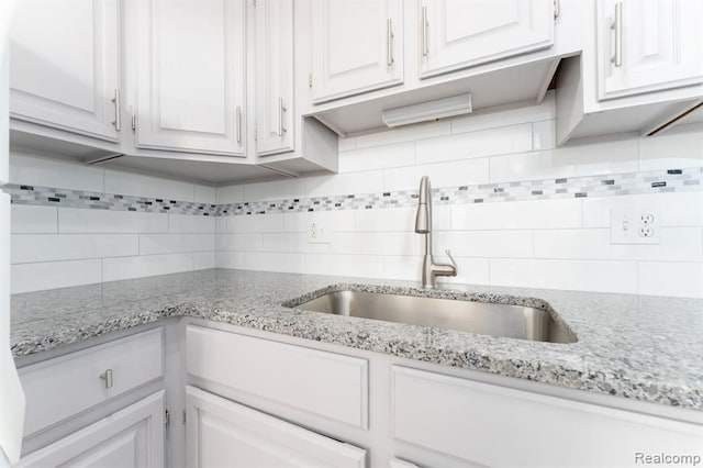 kitchen with white cabinets, light stone countertops, and sink