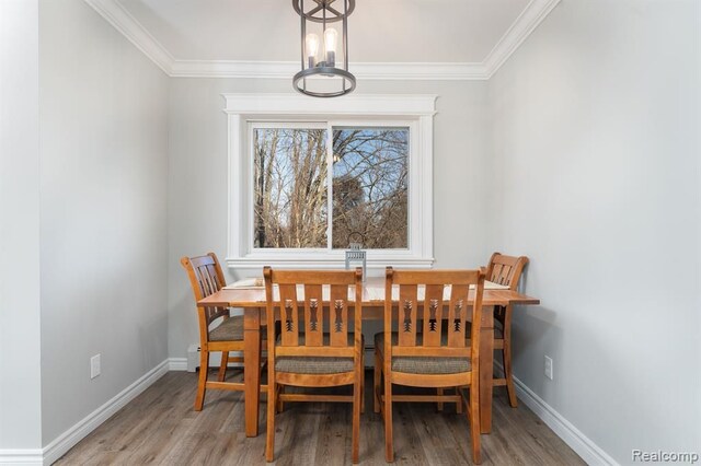 dining space with crown molding, baseboards, and wood finished floors