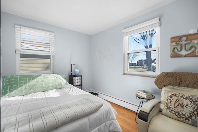 bedroom with baseboard heating and wood-type flooring