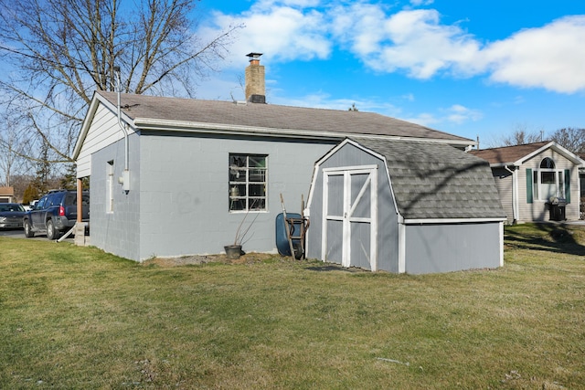 back of house featuring a lawn and an outdoor structure