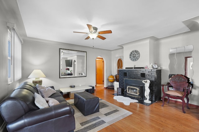 living room with hardwood / wood-style floors, a wood stove, ceiling fan, and plenty of natural light