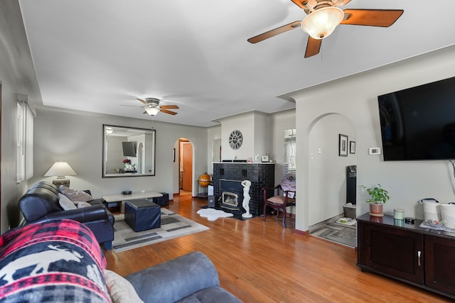 living room featuring light hardwood / wood-style floors, a wood stove, and ceiling fan