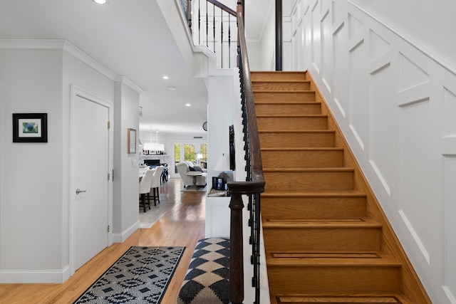 stairs with wood-type flooring and crown molding