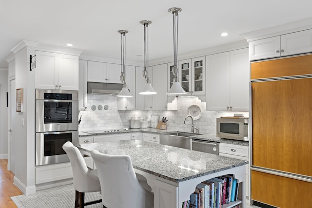 kitchen featuring decorative light fixtures, a center island, white cabinetry, and appliances with stainless steel finishes