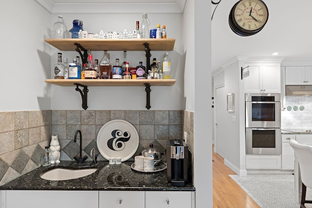 kitchen featuring dark stone counters, stainless steel double oven, extractor fan, sink, and white cabinets