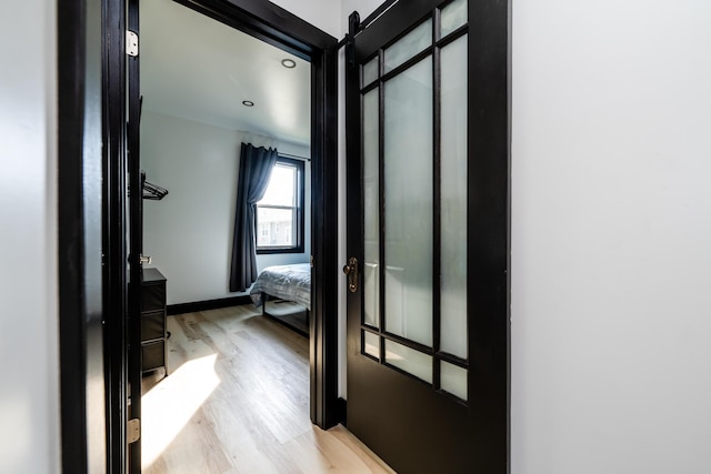 hall featuring a barn door and light hardwood / wood-style flooring