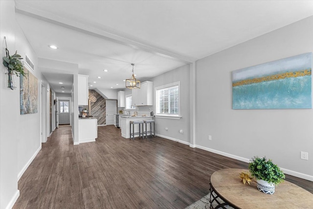 unfurnished living room with beamed ceiling, dark hardwood / wood-style flooring, and a chandelier