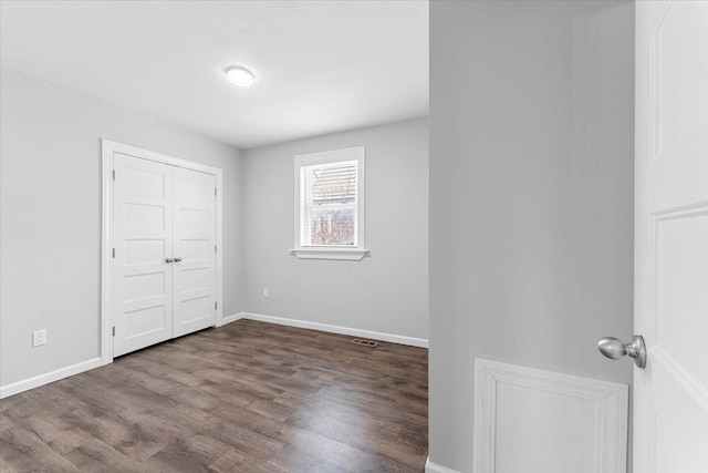 unfurnished bedroom with dark wood-type flooring and a closet