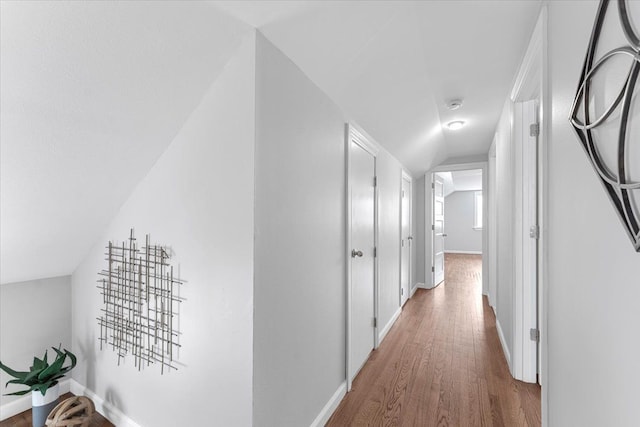 corridor featuring hardwood / wood-style flooring and vaulted ceiling