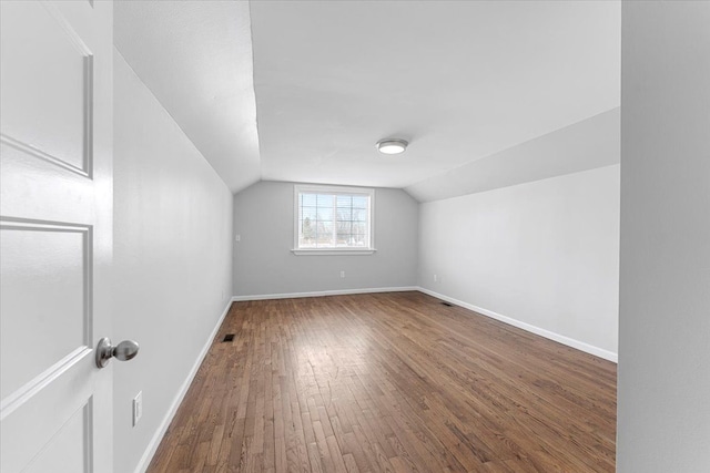 additional living space with lofted ceiling and hardwood / wood-style flooring