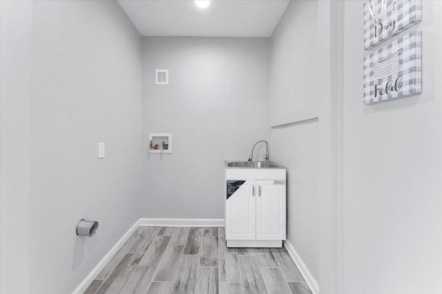 laundry area featuring cabinets, sink, washer hookup, and light hardwood / wood-style flooring