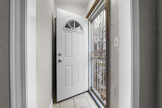 entryway with a textured ceiling and light tile patterned floors