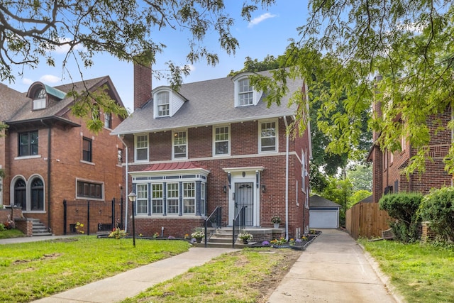 view of front of property with a garage, an outdoor structure, and a front lawn