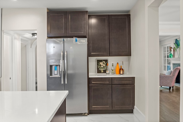 kitchen featuring dark brown cabinets, stainless steel fridge, and ornamental molding