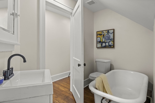 bathroom with sink, a tub to relax in, wood-type flooring, vaulted ceiling, and toilet