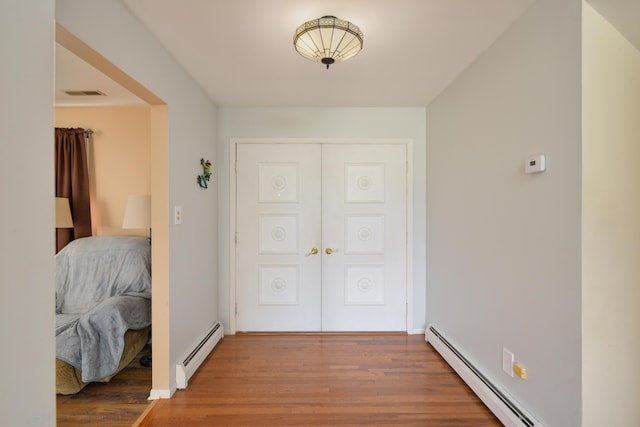 corridor with hardwood / wood-style floors and a baseboard radiator