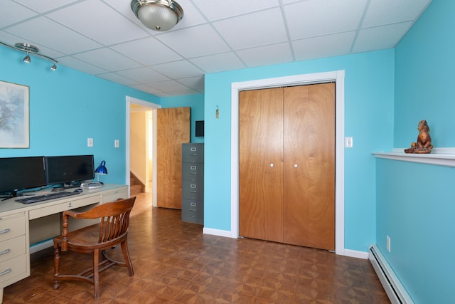 home office with a drop ceiling, dark parquet floors, and a baseboard heating unit