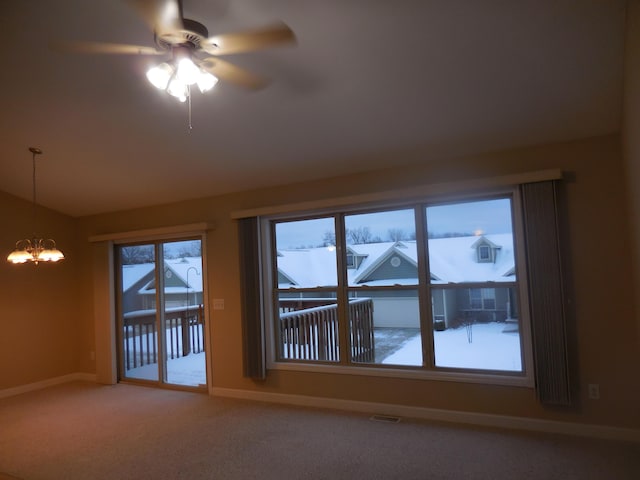 spare room featuring light carpet, visible vents, baseboards, and ceiling fan with notable chandelier