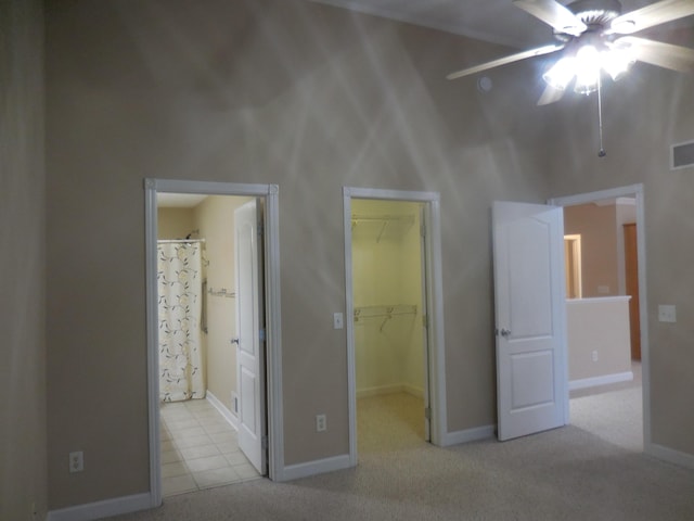 unfurnished bedroom featuring baseboards, ensuite bathroom, carpet, a spacious closet, and a closet