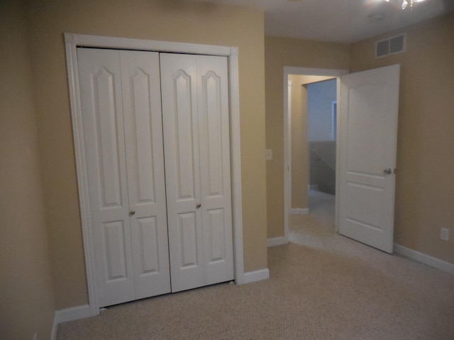 unfurnished bedroom with baseboards, visible vents, a closet, and light colored carpet