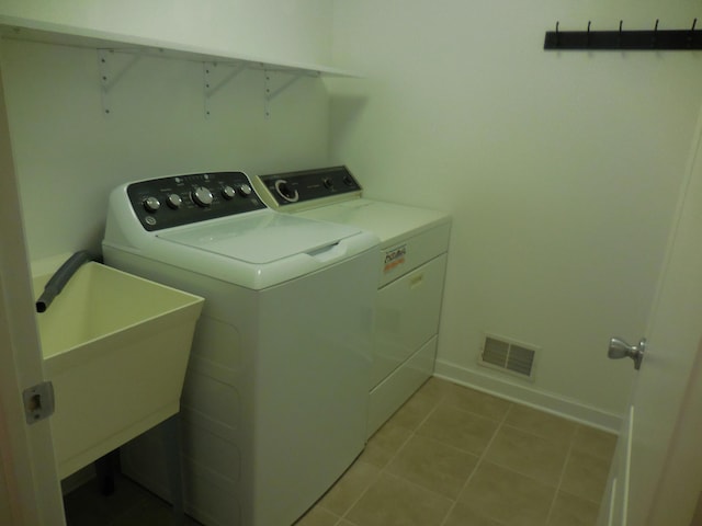 laundry room with light tile patterned floors, washing machine and dryer, laundry area, visible vents, and baseboards