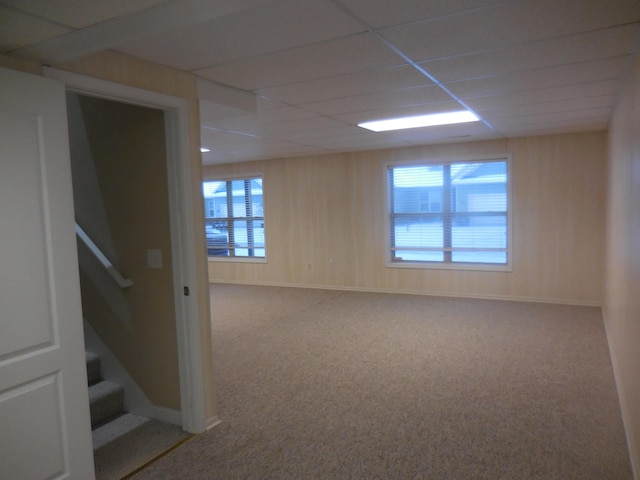 carpeted spare room featuring stairway, a paneled ceiling, and baseboards