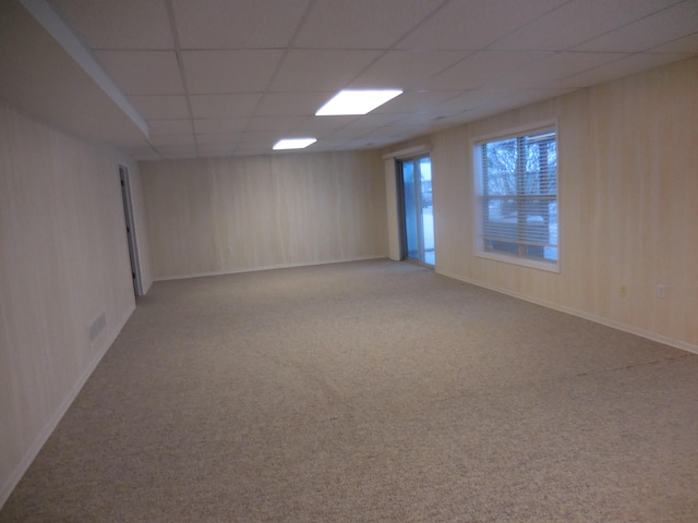 carpeted spare room featuring a drop ceiling, visible vents, and baseboards