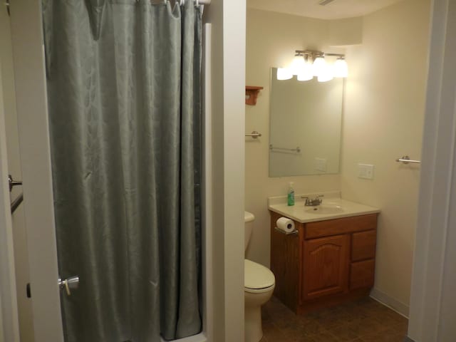 full bathroom featuring a shower with shower curtain, vanity, and toilet