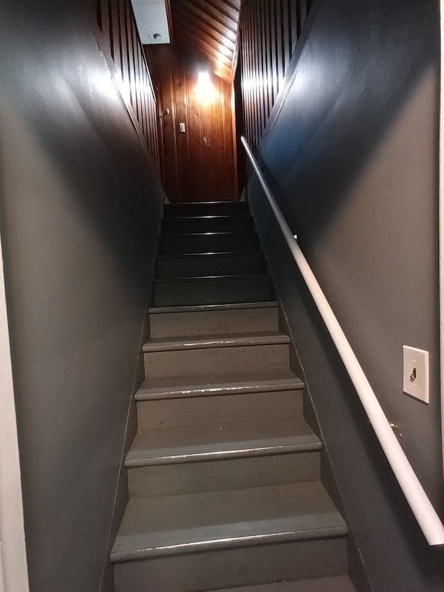 stairway featuring wood walls