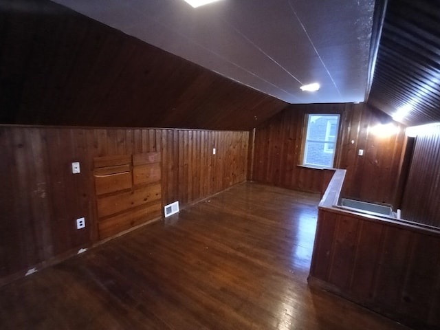 bonus room featuring dark hardwood / wood-style flooring, vaulted ceiling, and wood walls