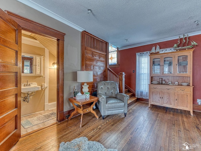 sitting room featuring hardwood / wood-style floors, crown molding, and a textured ceiling