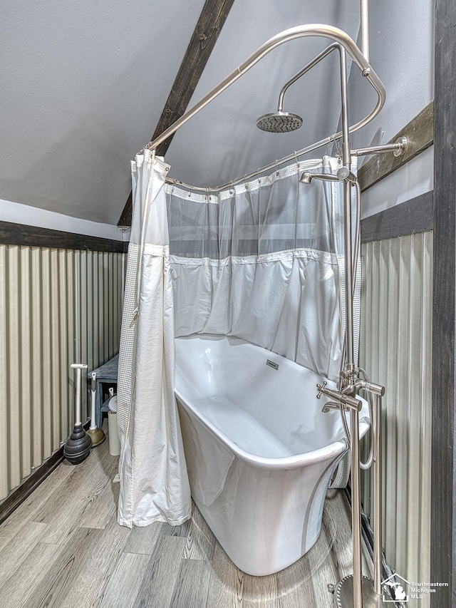 bathroom featuring hardwood / wood-style floors, vaulted ceiling, and a tub