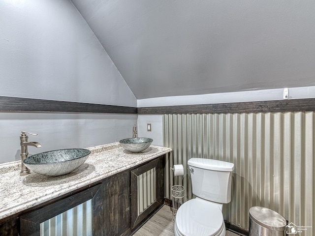 bathroom featuring vanity, toilet, and lofted ceiling