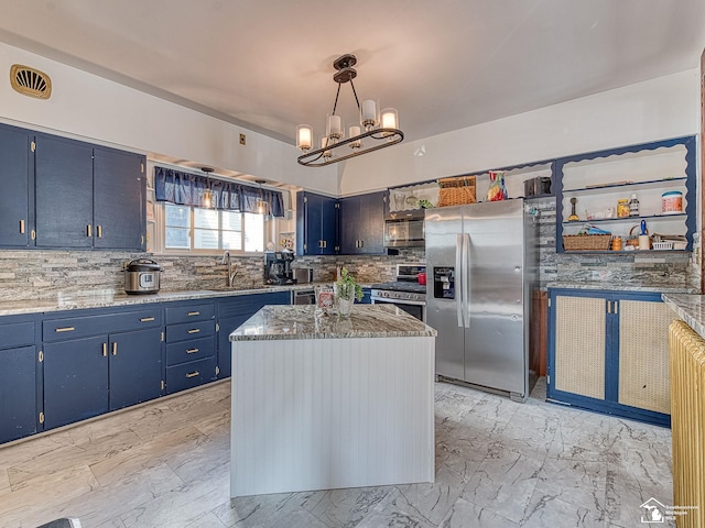 kitchen with appliances with stainless steel finishes, blue cabinets, sink, pendant lighting, and a center island