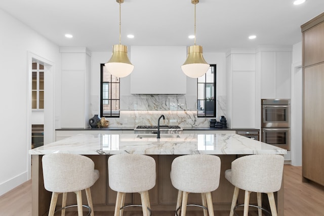 kitchen with white cabinetry, sink, a large island, and decorative light fixtures