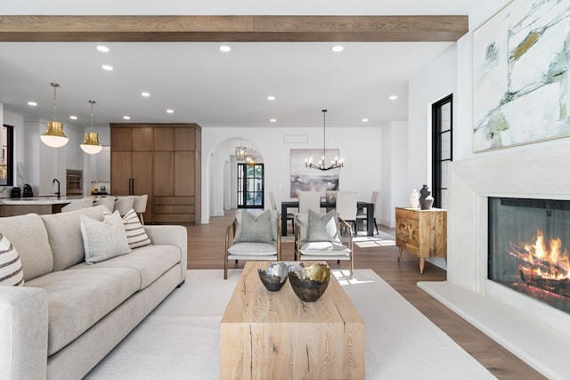 living room with a chandelier, beam ceiling, and hardwood / wood-style floors