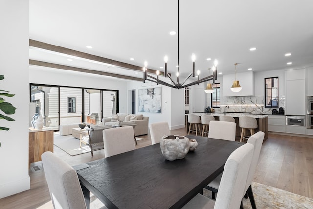 dining room with beam ceiling, light hardwood / wood-style floors, and a notable chandelier