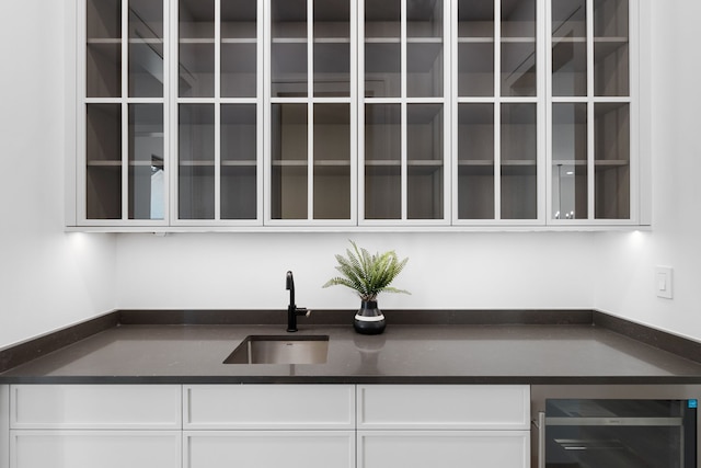 kitchen with white cabinets, sink, and beverage cooler