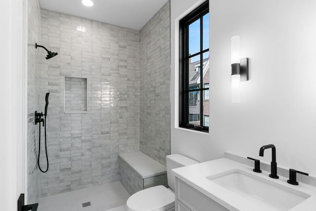 bathroom with vanity, a healthy amount of sunlight, toilet, and tiled shower