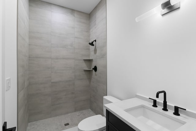 bathroom featuring tiled shower, vanity, and toilet